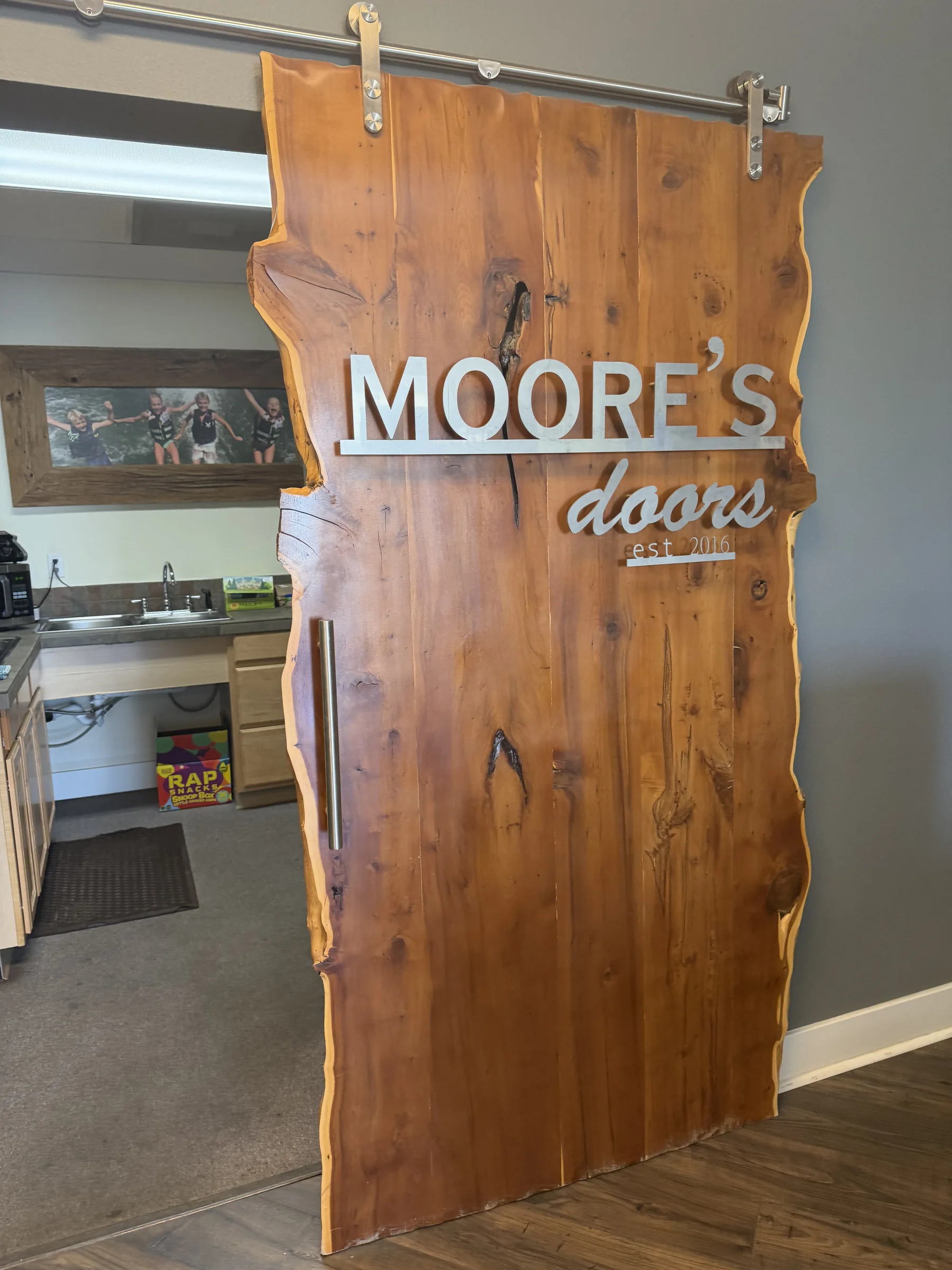 Rustic wood Moore's Doors sign displayed inside the Medford showroom